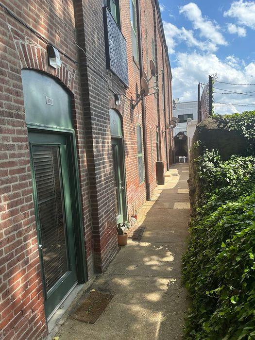 Brick walkway leading to Unit 101 with green entrance doors at Cotton Hill