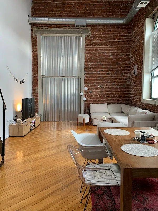 Living room with full-height exposed brick wall and ductwork at Cotton Hill loft